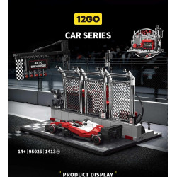 Xe F1 đỏ trắng đậu trên ô xuất phát caro trước cổng đèn và hàng rào lưới của bộ 12GO 95026