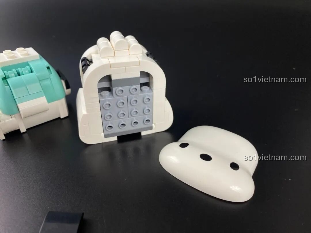 Quá trình lắp ráp phần đầu của figure Pochacco, ghép các mảnh trắng để tạo thành khuôn mặt.