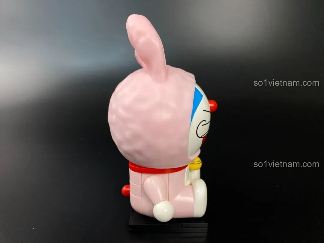 Mặt sau của mô hình Doraemon thỏ hồng với chi tiết đuôi đỏ và mũ trùm kín đầu.