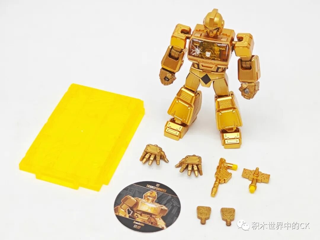 Ironhide mạ vàng đứng cạnh phụ kiện và đế tròn